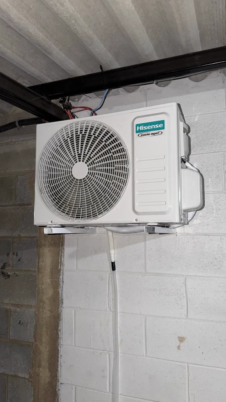 Condensadora Hisense instalada em suporte sob a cobertura, em parede de blocos.