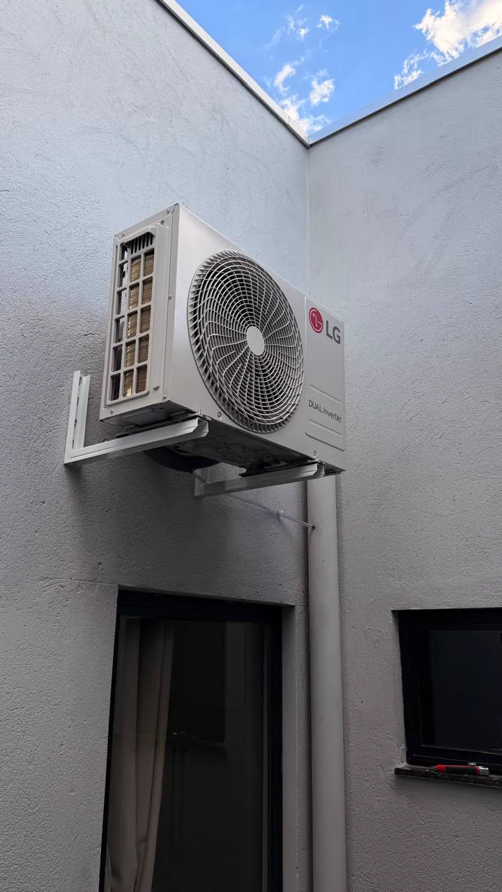 Condensadora LG fixada em suporte na parede externa, abaixo do céu aberto.